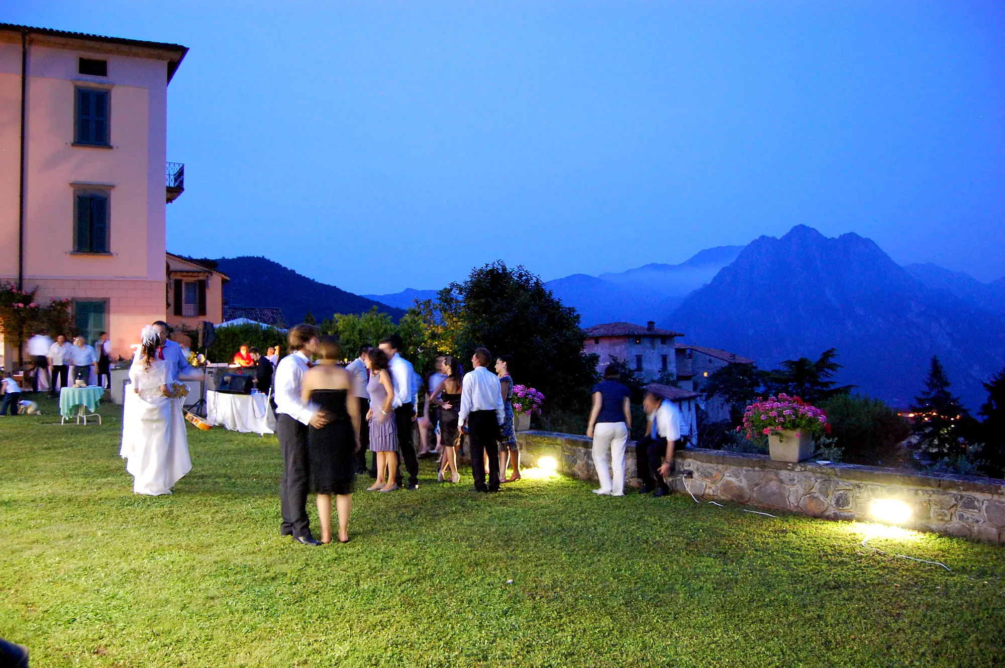 Les mariés et les invités sur la pelouse au coucher du soleil, avec les montagnes